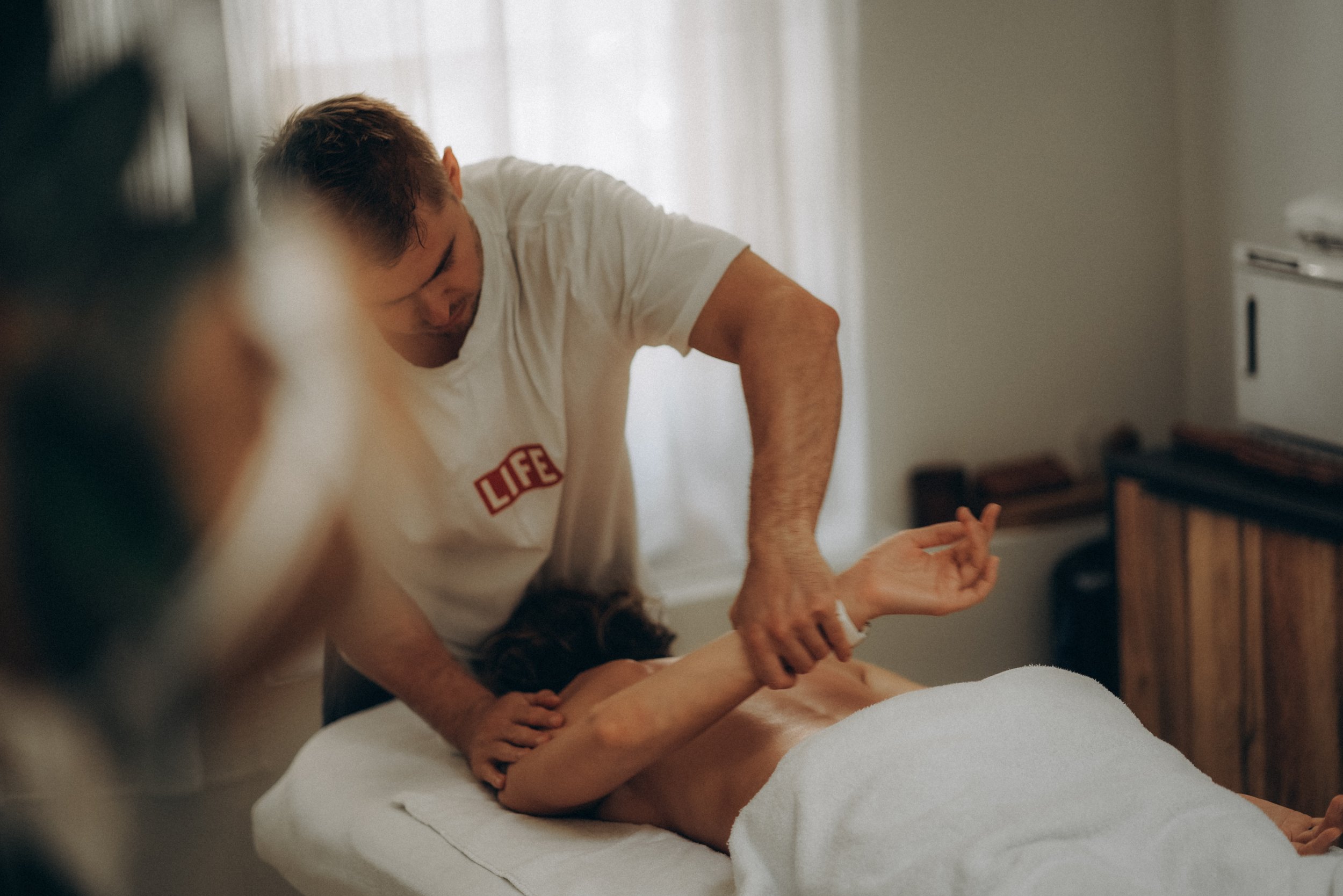 Masseur Alexey behandelt de schouder en arm van een cliënt op de massagetafel in de studio van Alex Therapy in Amsterdam