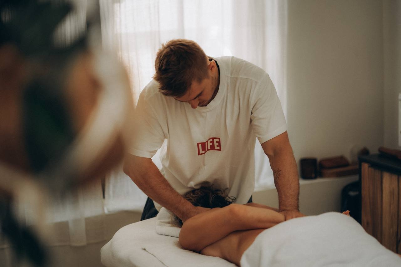 Alexey masseert de schouder en rug van een cliënt die op de massagetafel ligt bij Alex Therapy in Amsterdam