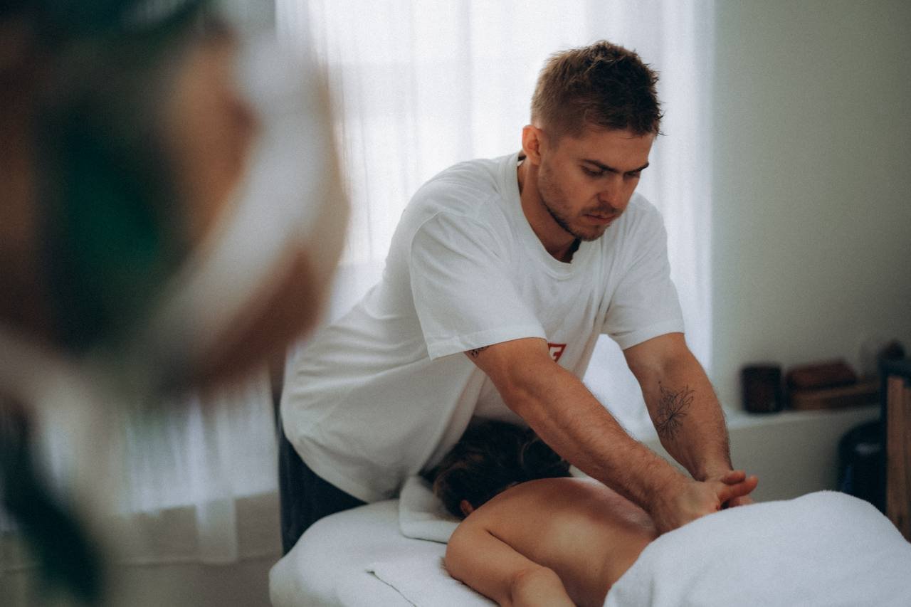 Alexey geeft een deep tissue massage op de rug van een cliënt in een lichte behandelkamer in Amsterdam